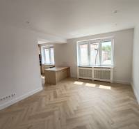 Bright living room in a two-room apartment with wooden flooring and windows.