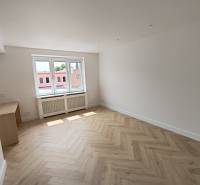 A room with a wooden floor and a large window in a 2-room apartment.