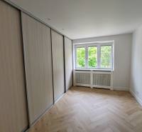 A room in a 2-room apartment with a built-in wardrobe and a window, light parquet flooring.