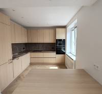 A kitchen in a 2-room apartment with wooden cabinets and built-in appliances.