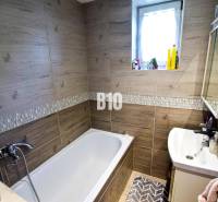 A bathroom in a family house with a bathtub, a sink, and a window.
