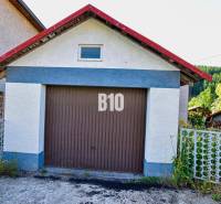 A garage at a family house in Turzovka, surrounded by greenery and a fence.