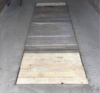 A wooden platform on the garage floor. Various items and storage space in the background.