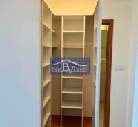A wardrobe in a one-room apartment with white shelves and a wooden floor.