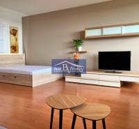 A studio apartment with a bed, TV, furniture, and wall decorations.
