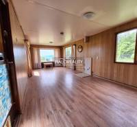 The interior of the cabin with wooden paneling, large windows, and a view of nature.