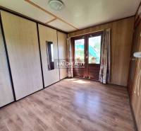 A room in a cabin with a wooden floor, large sliding doors, and built-in wardrobes.