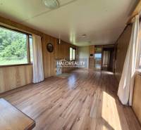 Interior of a wooden cabin with large windows and light flooring.