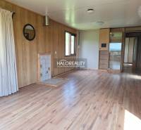Interior of a cabin with wooden paneling and laminate flooring, light walls and windows.