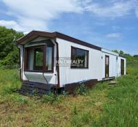 A mobile cottage in Boleráz surrounded by grass and trees in the background.