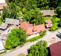 An aerial view of a family house in Púchov surrounded by greenery and nearby buildings.