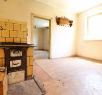 A kitchen in a family house with a tiled stove and wooden floor.