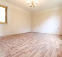 An empty room with a wooden floor and a window in a family house, neutral walls.