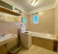 A bathroom in a 2-room apartment with a bathtub, sink, and washing machine.