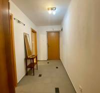 A hallway in a 2-room apartment with wooden doors and a mirror on the table.