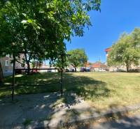 Peaceful Studentská Street in Trnava with apartment buildings and a green park in the background.