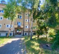 An apartment building on Študentská Street in Trnava surrounded by trees and a green garden.