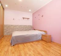 A bedroom in a 3-room apartment with wooden flooring, pink walls, and furniture.