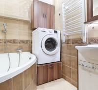 Bathroom with a bathtub, washing machine, and cabinets in a 3-room apartment.