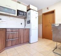 Kitchen in a 3-room apartment with wooden cabinets, appliances, and a dining table.