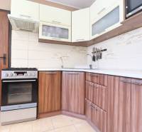 A kitchen in a 3-room apartment with a stove and wooden cabinets, light tiles.