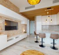 Living room in a 2-room apartment with a brick wall, kitchen island, and bar stools.