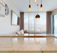 A kitchen countertop made of granite stone in a 2-room apartment with a brick wall and lighting.