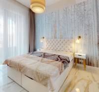 A bedroom with a nature motif on the wallpaper, a large window, and a mirrored wardrobe in a 2-room apartment.