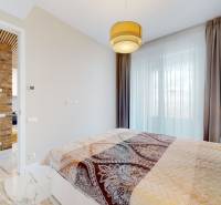 A bedroom in a two-room apartment with a brick wall and a curtain.