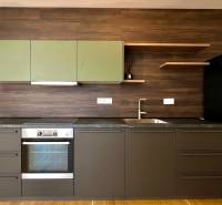 A kitchen in a 2-room apartment with dark furniture and built-in appliances.