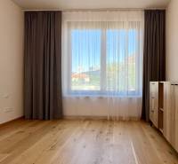 A spacious room with wooden flooring, curtains, and a dresser in a 2-room apartment.