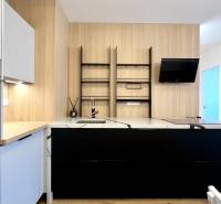 A kitchen in a 2-room apartment with white and black cabinets, a built-in oven, and wooden elements.