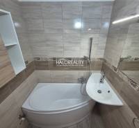 Bathroom with a shower tub and sink in a 3-room apartment, tiles with a natural pattern.