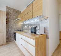 A kitchen in a 3-room apartment with wooden furniture and brick wall cladding, appliances.