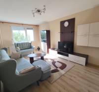 Living room in a 3-room apartment with a sofa, TV furniture, and a window in the background.