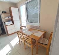 Dining table with chairs in the kitchen of a 3-room apartment, next to a kitchen cabinet.