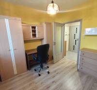 A room with furniture in a 3-room apartment, wooden floor, yellow walls, desk, chair.
