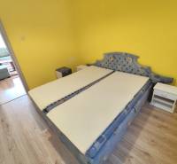 Bedroom in a 3-room apartment with a yellow wall, bed, and nightstands.