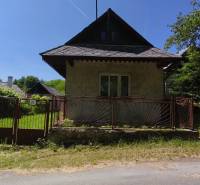 A family house in Čelovce with a garden, fence, and trees, sunny weather.