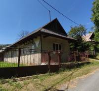 A family house in Čelovce with a wooden fence and a gable roof in a natural setting.