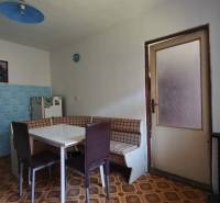 Kitchen in a family house with corner seating, blue tiles, and a table.