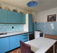 A kitchen in a family house with blue kitchen cabinets and a corner bench.
