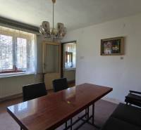 Dining room with a wooden table, curtain, and chandelier in a family house.