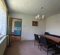 Dining room with seating and a chandelier next to the kitchen in a family house.