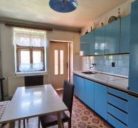 A kitchen in a family house with a blue kitchen unit, a dining table, and a bench.