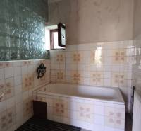 A bathroom in a family house with tiles and a bathtub, decorated with vintage motifs.