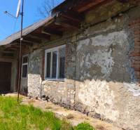 A family house in Čelovce with a plastered wall and a satellite dish in the courtyard.