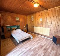 Wooden interior of a cabin with a bed and wooden floor.