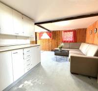 The interior of a cottage with a white kitchen unit and a comfortable sofa.