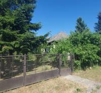 A family house in Sečovce on Mostová Street, surrounded by trees and a fence.